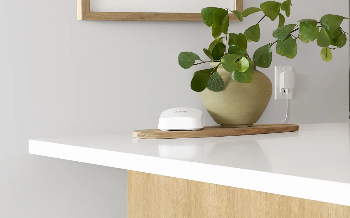 eero 7 beside a green plant on a warm residential kitchen counter