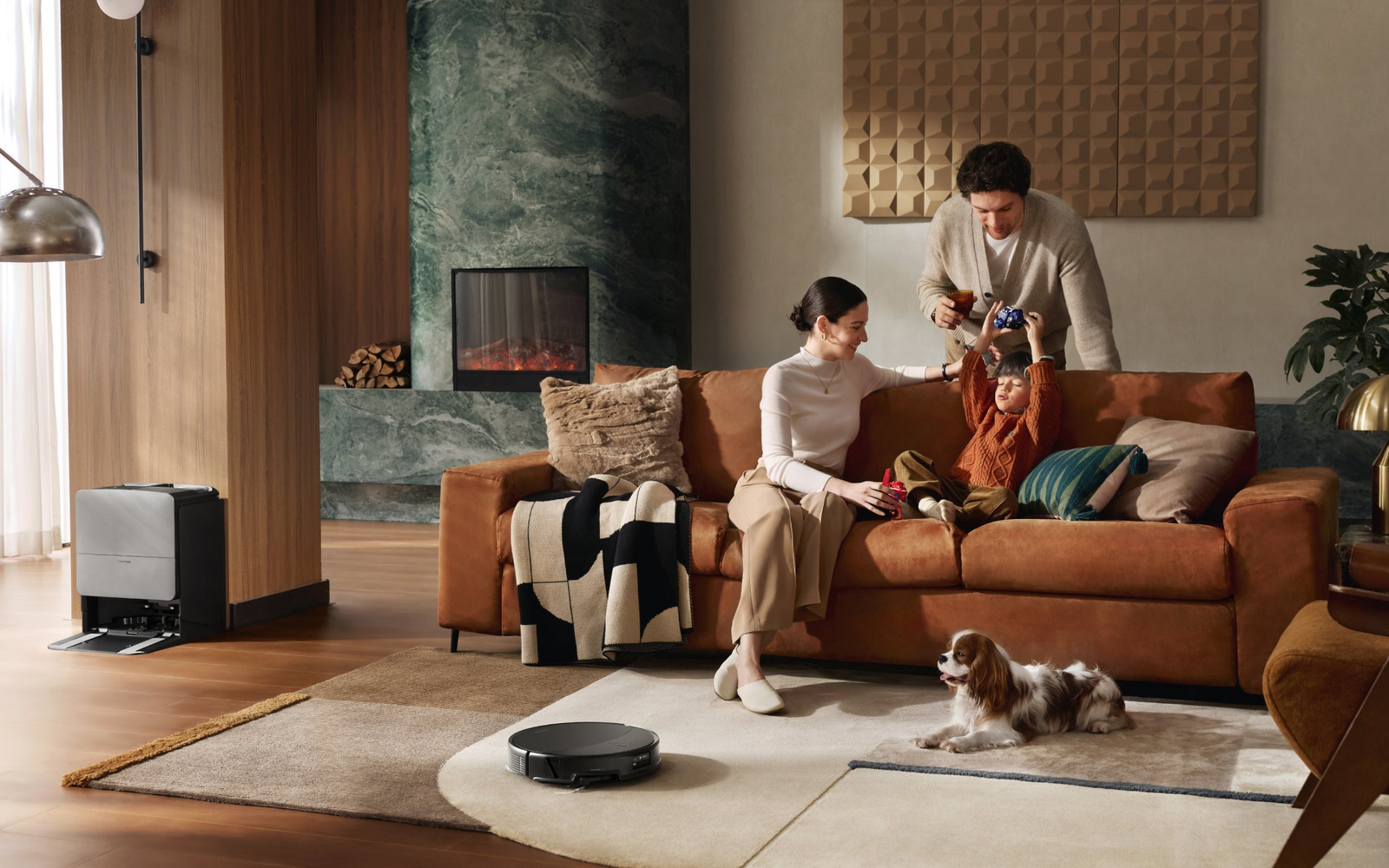 Roborock Saros 20 robot vacuum and dock in a warm living room with an oak floor and dark-green fireplace